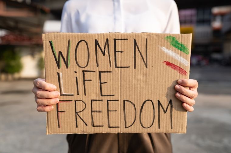 Person holding a sign saying Woman Life Freedom.